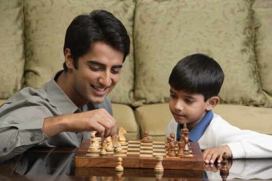 Gifted boy playing chess with his father
